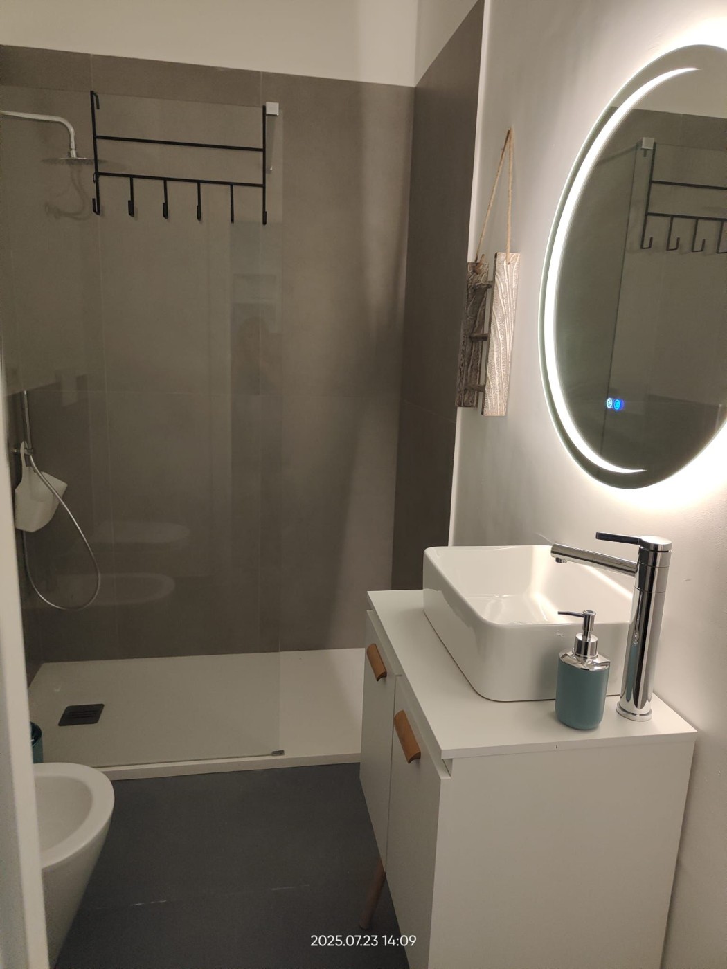 Bagno moderno con doccia, lavabo e specchio illuminato