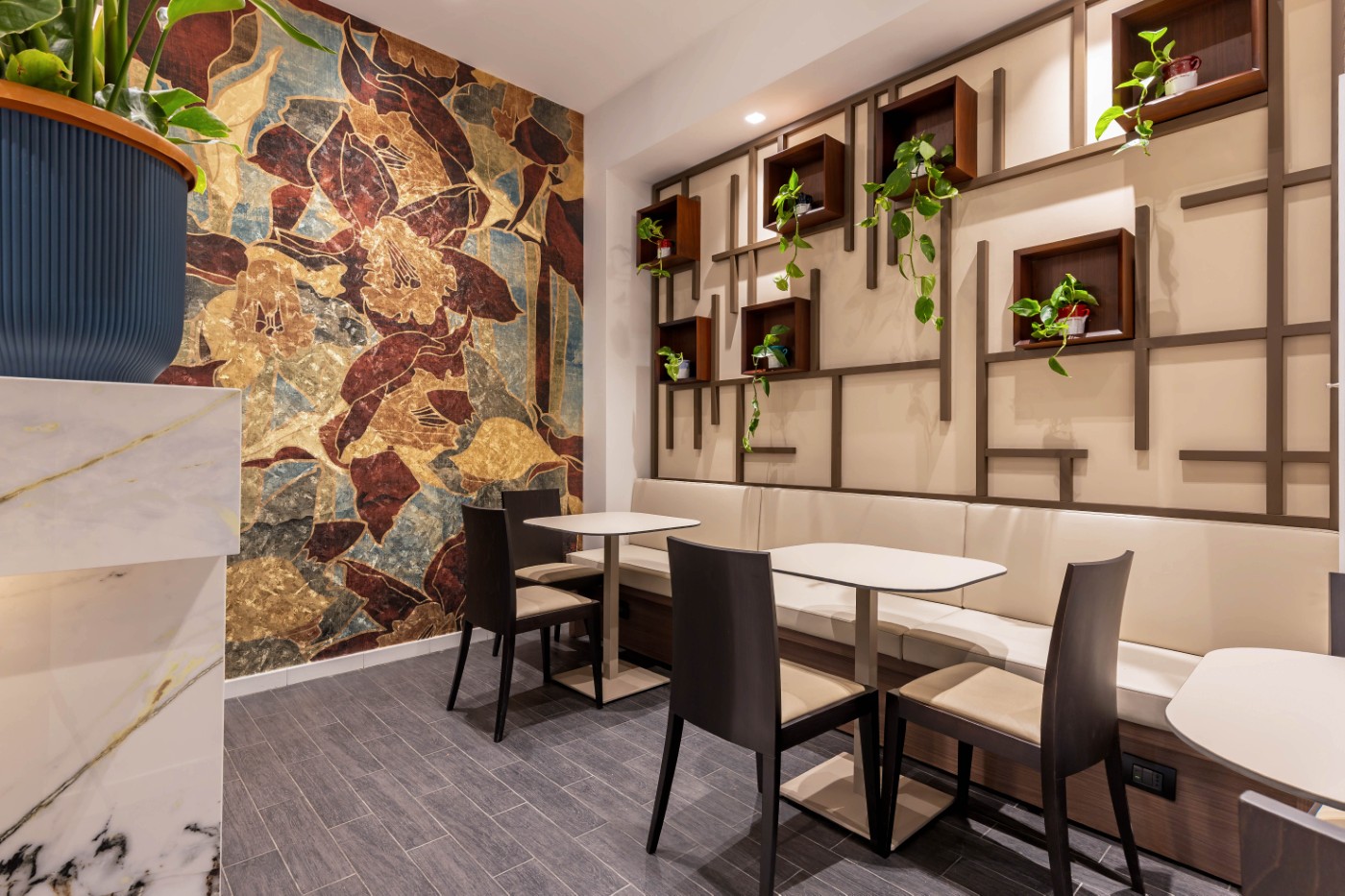 Sala bistrot con tavolini, parete decorata e mensole